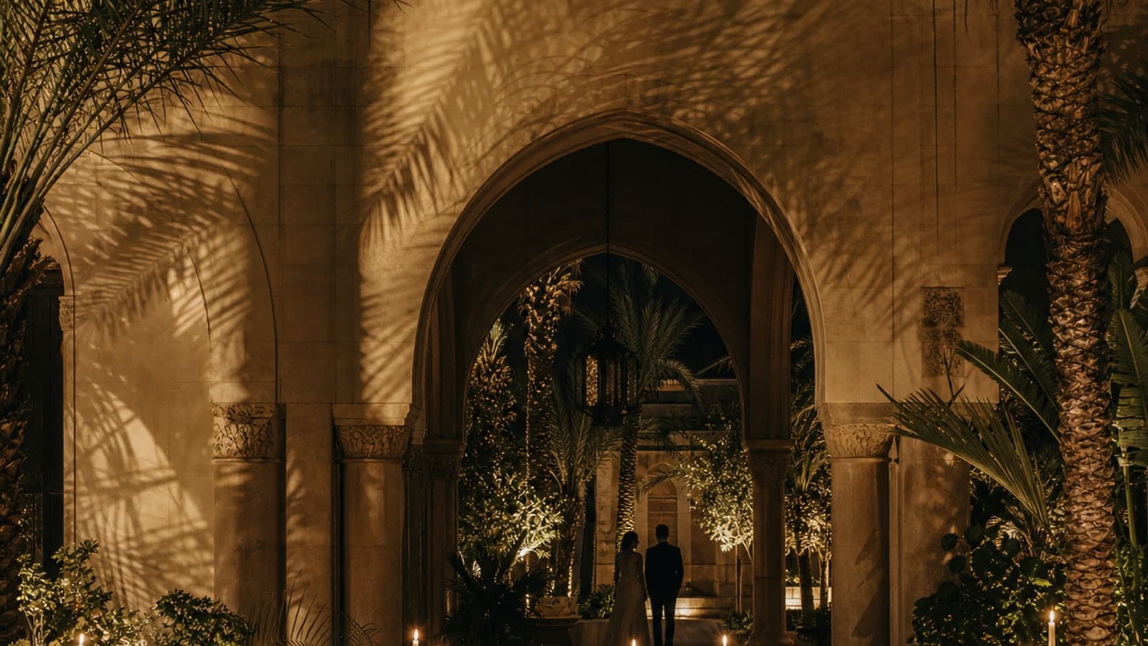 A linen wedding table beneath deep palm shadows